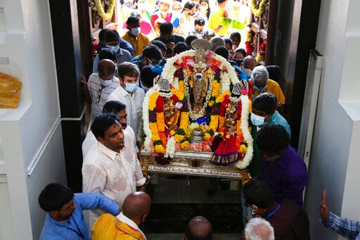 Devotos e voluntários do Templo Sri Venkateswara carregam uma divindade de volta para o templo durante o Maha Kumbhabhishekam. (AP)
