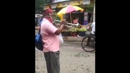 The image shows the man playing a song by RD Burman on the trumpet.