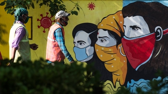 People walk past a graffiti depicting awareness on masks. (Photo by Pratik Chorge/Hindustan Times)