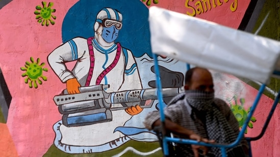 A rickshaw puller takes a break near a wall mural depicting a frontline Covid-19 coronavirus worker, in New Delhi on June 29, 2021. (AFP) A rickshaw puller takes a break near a wall mural depicting a frontline Covid-19 coronavirus worker, in New Delhi on June 29, 2021. (AFP)