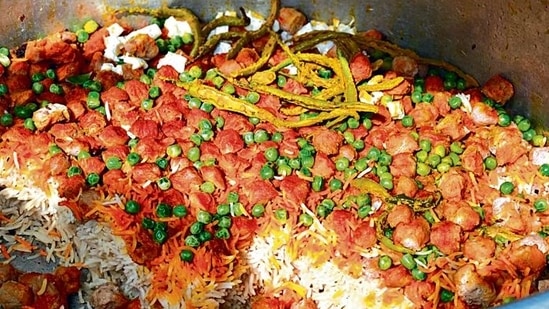 This late morning the biryani is inside a huge deg, or cauldron. On lifting the lid, you glimpse at steaming saffron-shaded rice cratered with vegetables and whole green chilies. This late morning the biryani is inside a huge deg, or cauldron. On lifting the lid, you glimpse at steaming saffron-shaded rice cratered with vegetables and whole green chilies.