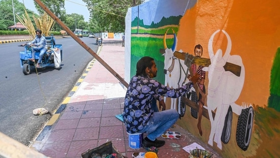 An artist paints a mural depicting a farmer on his bullock cart while travelling sugarcane juice vendor passes by in the background, in New Delhi on June 29. Another IMD official said the delay in monsoon over parts of northwest India, including Delhi, was another reason behind the high recordings. (Prakash Singh / AFP) An artist paints a mural depicting a farmer on his bullock cart while travelling sugarcane juice vendor passes by in the background, in New Delhi on June 29. Another IMD official said the delay in monsoon over parts of northwest India, including Delhi, was another reason behind the high recordings. (Prakash Singh / AFP)