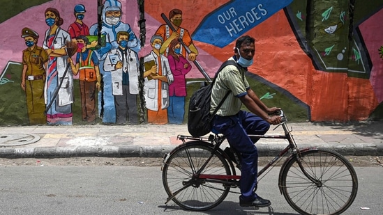 A cyclist passes by a wall mural depicting frontline Covid-19 coronavirus workers, in New Delhi on June 29. Delhi has this year experienced a relatively cooler summer season, with temperatures during April, May and even till the second week of June recording lower than normal. However, the conditions changed over the last one week, with the temperatures rising above the 40 degrees mark, HT reported. (Money Sharma / AFP) A cyclist passes by a wall mural depicting frontline Covid-19 coronavirus workers, in New Delhi on June 29. Delhi has this year experienced a relatively cooler summer season, with temperatures during April, May and even till the second week of June recording lower than normal. However, the conditions changed over the last one week, with the temperatures rising above the 40 degrees mark, HT reported. (Money Sharma / AFP)