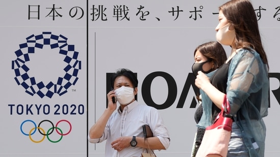 People walk past an Tokyo Olympics logo in Tokyo. (AP) People walk past an Tokyo Olympics logo in Tokyo. (AP)