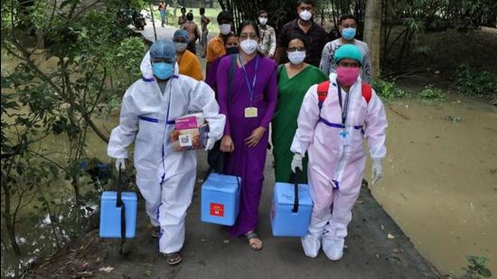 Healthcare workers carry Covishield doses to inoculate villagers during a door-to-door vaccination and testing drive at Uttar Batora Island in Howrah district in West Bengal state, India. (REUTERS)