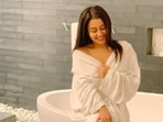 Neha Kakkar poses inside her bathroom, dressed in a bathrobe.
