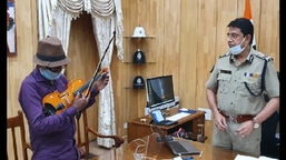 The image shows Commissioner of Police, Kolkata Soumen Mitra gifting a new violin to Bhagaban Mali.