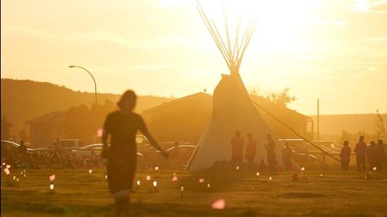A file photo of a woman walking through a field where flags and solar lights mark the site where human remains were discovered in unmarked graves at the former Marieval Indian Residential School site on Cowessess First Nation, Saskatchewan on June 26, 2021. (AFP/FILE) A file photo of a woman walking through a field where flags and solar lights mark the site where human remains were discovered in unmarked graves at the former Marieval Indian Residential School site on Cowessess First Nation, Saskatchewan on June 26, 2021. (AFP/FILE)