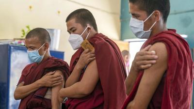 Buddhist monks hold their arms after receiving the Covid-19 vaccine at a vaccination centre in Dharamshala. (Bloomberg) Buddhist monks hold their arms after receiving the Covid-19 vaccine at a vaccination centre in Dharamshala. (Bloomberg)