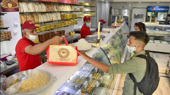 People purchasing sweets from a sweet shop in Ludhiana on Friday. (Harsimar Pal Singh/HT)