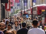 Pedestrians, some wearing face coverings due to Covid-19, walk past shops on Oxford Street in central London on June 7, 2021 (AFP)