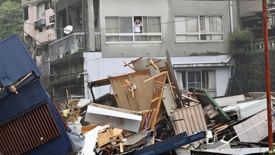 A resident looks from a window at houses that have been damaged by a mudslide following heavy rain at Izusan district in Atami, Japan on July 3. Dozens of homes may have been buried in Atami, a town known for hot springs, according to Shizuoka prefecture spokesman Takamichi Sugiyama, AP reported.(Kyodo via REUTERS)