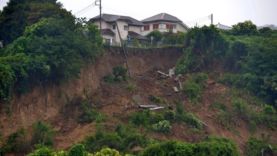 First responders observe a landslide caused by heavy rains in Zushi, Kanagawa prefecture, west of Tokyo on July 3. Torrential rains have slammed parts of Japan starting earlier this week. Experts said dirt had been loosened, increasing landslide risks in a country filled with valleys and mountains.(Kyodo News via AP)
