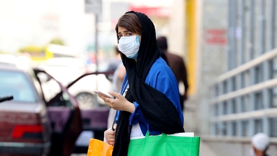 An Iranian woman, mask-clad due to the coronavirus pandemic, waits to cross a street in the capital Tehran, on July 3, 2021.(AFP)