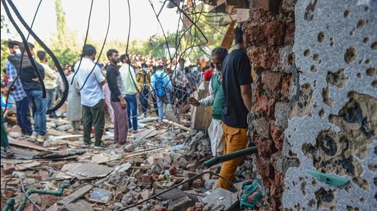 Villagers gather near a house which was partially damaged during an encounter between security forces and militants at Rajpora in Pulwama district on Friday. (PTI)