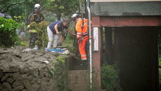 Firefighters help a resident evacuate after a mudslide at the Izusan district in Atami on July 3. Evacuation warnings were issued for a wide area, including the so-called “Level 5,” which is the highest possible alert.(Kyodo News via AP)