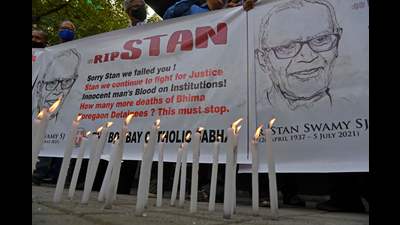 People hold posters next to candles outside the church holding memorial mass for Father Stan Swamy, Mumbai, July 6, 2021 (AFP)