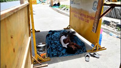 A worker takes a nap under a makeshift board to protect himself from scorching heat along a roadside in New Delhi. (File photo)
