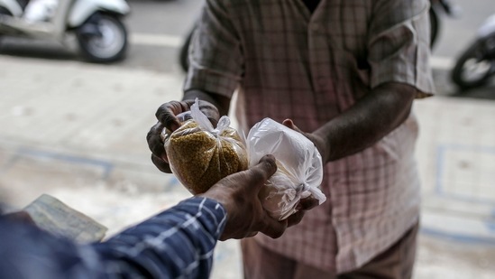 A sales assistant hands produce to a customer at a grocery store, known as a kirana, in Bengaluru, India, on Monday, Jun. 21, 2021.(Bloomberg)