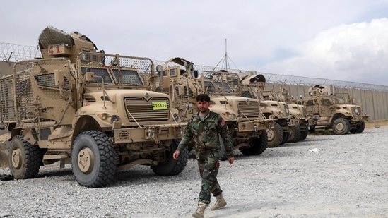 An Afghan army soldier walks past Mine Resistant Ambush Protected vehicles, MRAP, that were left after the American military left Bagram air base, in Parwan province north of Kabul, Afghanistan, Monday, July 5, 2021. (AP)