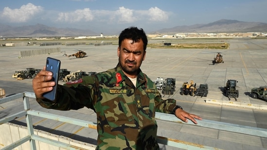 An Afghan National Army (ANA) soldier take a selfie with his mobile phone inside the Bagram air base after all US and NATO troops left, on July 5. Neighbourhoods and markets in the shadow of the base are left ruing the past and bracing for what comes next.(Wakil Kohsar / AFP)