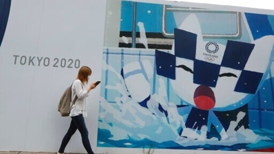 A woman walks by posters to promote the Tokyo Olympics in Tokyo, Monday, July 5, 2021.(AP)