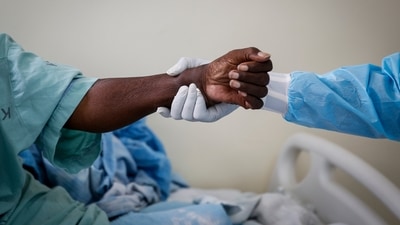 A medical worker (R), helps a coronavirus patient (L), to sit up in the Covid-19 intensive care unit at Kenyatta National Hospital, in Nairobi, Kenya on April 14. With the advent of the vaccine, deaths per day have plummeted to around 7,900, after topping out at over 18,000 a day in January. (Brian Inganga / AP)