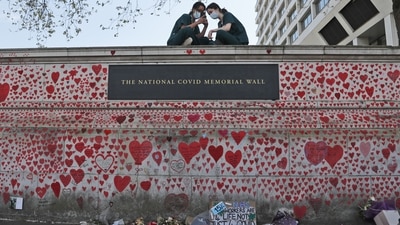Nurses from the nearby St Thomas' hospital sit atop the National Covid Memorial Wall in London, England on April 27. The figure is widely believed to be an undercount because of overlooked cases or deliberate concealment, AP reported. (Frank Augustein / AP)