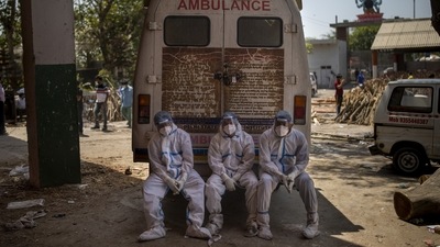 Exhausted workers, who bring dead bodies for cremation, sit on the rear step of an ambulance inside a crematorium, in New Delhi on April 24. Instead of treating the crisis as a “me-and-myself-and-my-country” problem, Linsatrand said, “we need to get serious that this is a worldwide problem that needs worldwide solutions.” (Altaf Qadri / AP)