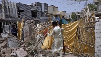 Residents remove a gate from their damaged house at the site of a car bombing in Lahore, Pakistan, on June 24, 2021. (AP) Residents remove a gate from their damaged house at the site of a car bombing in Lahore, Pakistan, on June 24, 2021. (AP)