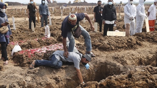 A man falls to the ground as he weeps during the burial of a relative who died of Covid-19, at the Rorotan Cemetery in Jakarta, Indonesia on July 7. The US has the world's highest reported death toll, at over 600,000, or nearly 1 in 7 deaths, followed by Brazil at more than 520,000. India has recorded more than 405,000 deaths so far.(Tatan Syuflana / AP)