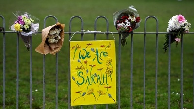 Flowers and a placard are seen on a fence at a memorial site at the Clapham Common Bandstand, following the kidnap and murder of Sarah Everard, in London. (REUTERS)