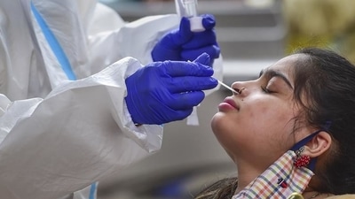 A health worker collects a swab sample of a passenger for a Covid-19 test at a railway station in Kerala on July 7 (PTI) A health worker collects a swab sample of a passenger for a Covid-19 test at a railway station in Kerala on July 7 (PTI)