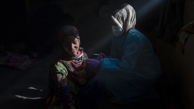 Najma Begum, a shepherd, reacts as she receives the Covishield vaccine for Covid-19 from Masrat Farid, a healthcare worker, in Gagangeer, northeast of Srinagar on June 22. (Dr Yasin / AP)