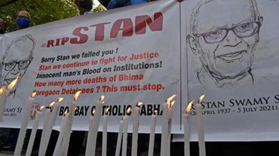 People hold posters next to candles outside the church holding memorial mass for activist and Jesuit priest Father Stan Swamy, in Mumbai on July 6. (AFP)