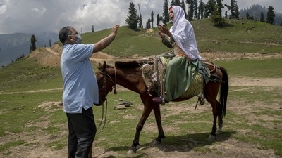 Dr. Tajamul-Hussain Khan, chief medical officer unsuccessfully tries to convince a nomad woman sitting on horseback who refused to let her 30-year-old son to be vaccinated during a Covid-19 vaccination drive in Tosamaidan, southwest of Srinagar on June 21. (Dar Yasin / AP)