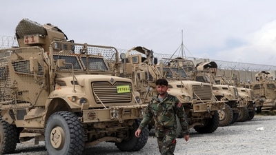 An Afghan army soldier walks past Mine Resistant Ambush Protected vehicles, MRAP, that were left after the American military left Bagram air base, in Parwan province north of Kabul. (AP)