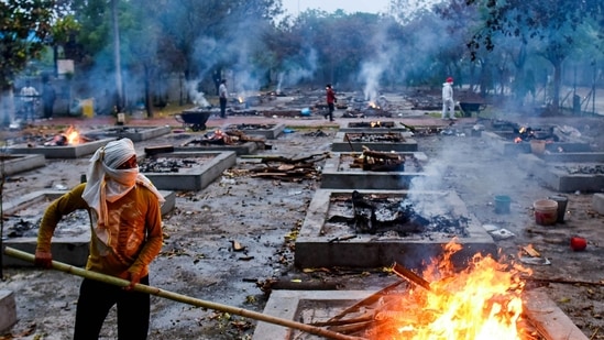 A worker stoking a funeral pyre during cremations of Covid-19 victims at Sarai Kale Khan crematorium, in New Delhi, India, on Thursday, May 06, 2021. (Photo by Amal KS / Hindustan Times)