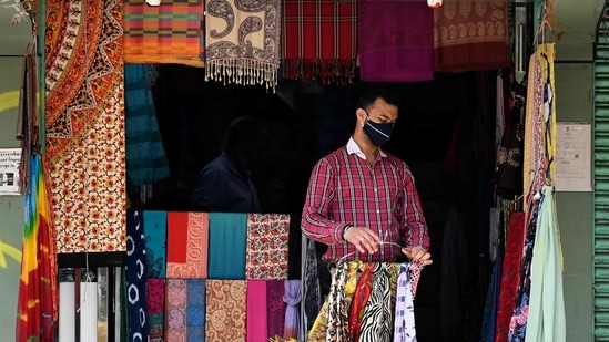 A vendor wearing a facemask as a preventive measure against the spread of the Covid-19 coronavirus, opens his shop at a market in New Delhi.(AFP) A vendor wearing a facemask as a preventive measure against the spread of the Covid-19 coronavirus, opens his shop at a market in New Delhi.(AFP)