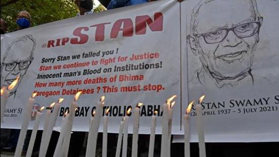 People hold posters next to candles outside the church holding memorial mass for activist and Jesuit priest Father Stan Swamy, in Mumbai on July 6. (AFP)