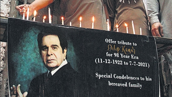 Residents outside the remains of his ancestral home, in Peshawar, Pakistan. light candles next to a poster of Bollywood icon Dilip Kumar. Kumar died on Wednesday at a Mumbai hospital. (AP)