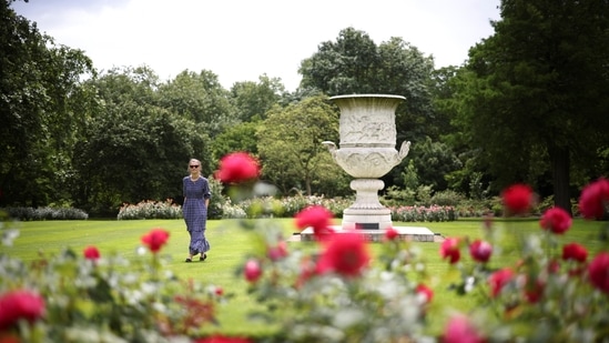 Palace staff member walks through the Rose Garden at The Garden of Buckingham Palace, during a preview day before it opens to the public, in London, Britain, July 8, 2021. Visitors will be able to see the gardens' 156-metre herbaceous border, its beehives, and plane trees planted by and named after Queen Victoria and Prince Albert, and picnic on its manicured lawns while treating themselves to some royal-themed picnic accessories such as a blanket and cotton napkins.(REUTERS)