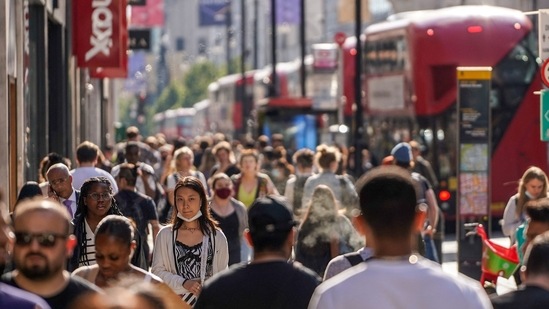Pedestrians, some wearing face coverings due to Covid-19, walk past shops on Oxford Street in central London on June 7, 2021.