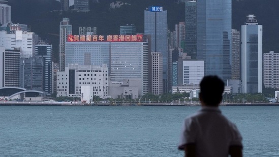 In this file photo taken on June 29, 2021, a man looks at a building with a LED billboard displaying a slogan celebrating the 100th anniversary of the Chinese Communist Party and the 24th anniversary of Hong Kong's return to China. (AFP)