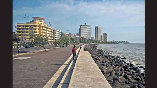A solitary walker takes photographs of the sea at Marine Drive on a weekday evening. (Pratik Chorge / HT)