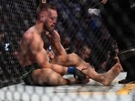 Conor McGregor holds his leg after suffering an injury against Dustin Poirier during UFC 264 at T-Mobile Arena