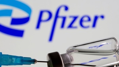 Syringe and vial are seen in front of the displayed new Pfizer logo in this illustration (Reuters)