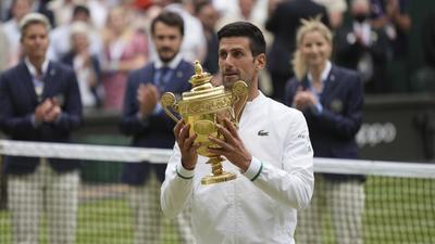 Serbia's Novak Djokovic holds his winner's trophy and celebrates his victory over Italy's Matteo Berrettini after the Wimbledon final in London on Sunday. (AP)