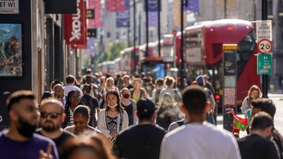 Pedestrians, some wearing face coverings due to Covid-19, walk past shops on Oxford Street in central London. (AFP)