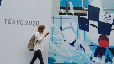 A woman walks by posters to promote the Tokyo Olympics in Tokyo. (AP) A woman walks by posters to promote the Tokyo Olympics in Tokyo. (AP)